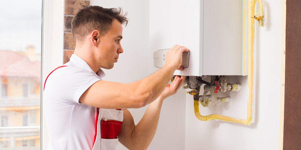 The plumber repairs a boiler at the kitchen